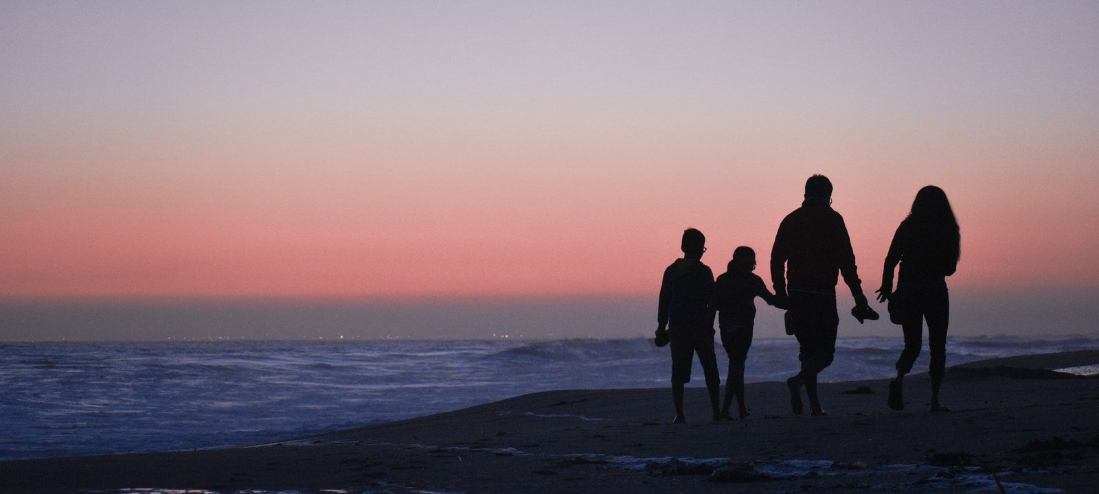 silhouette of 3 men and woman standing on beach during sunset